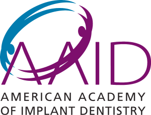 The image is a logo with a stylized graphic resembling a human profile in blue and purple hues, set against a white background with text. The text includes  AID  prominently displayed at the top, and below it, there s additional text that reads  American Academy of Implant Dentistry.