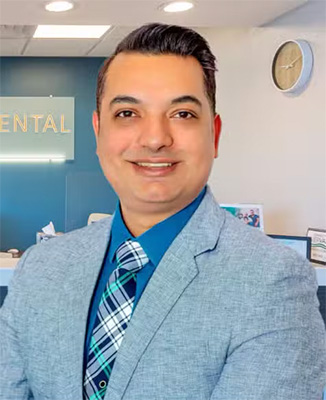 The image features a man standing in an office environment with a professional attire, smiling at the camera.