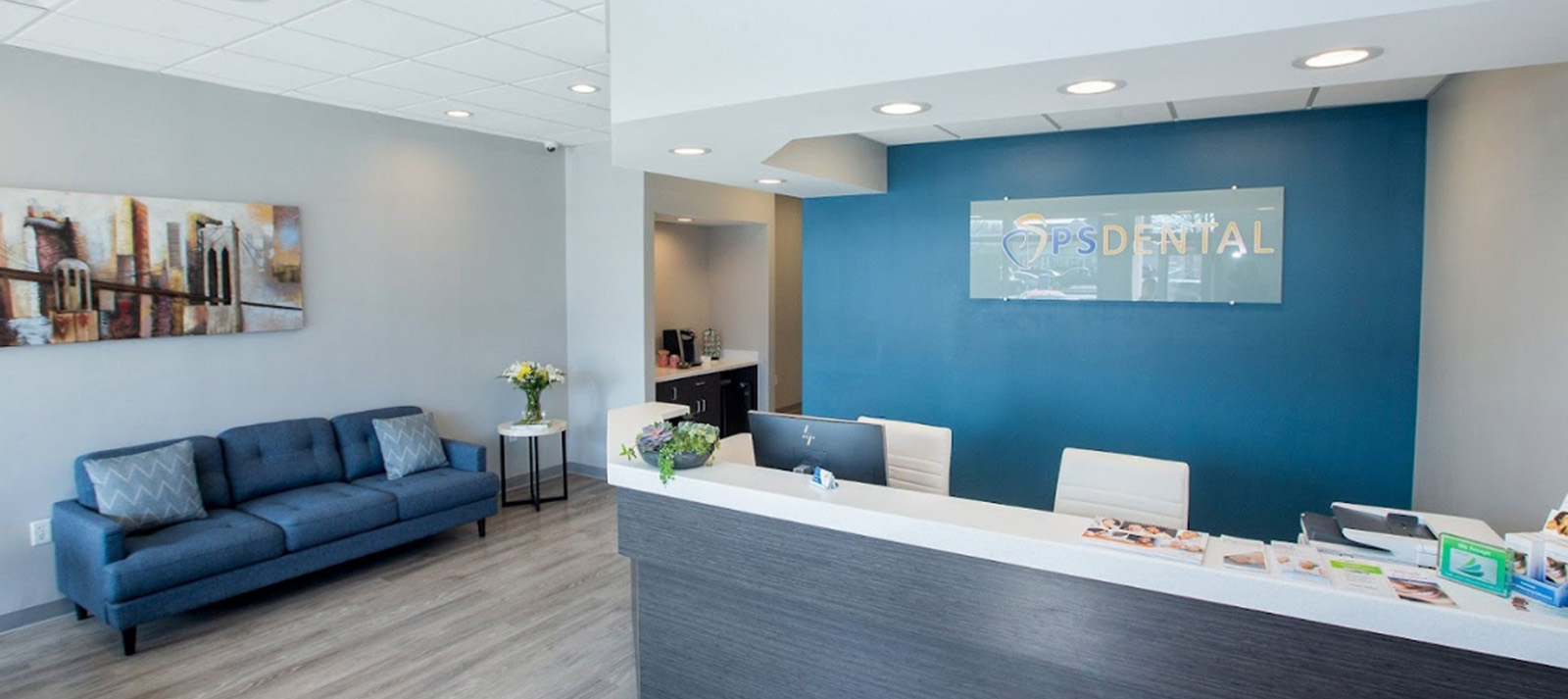 The image shows an interior space with modern furnishings, including a couch, chairs, and a reception desk with a blue wall backdrop. A sign reading  dental  is visible above the reception area.