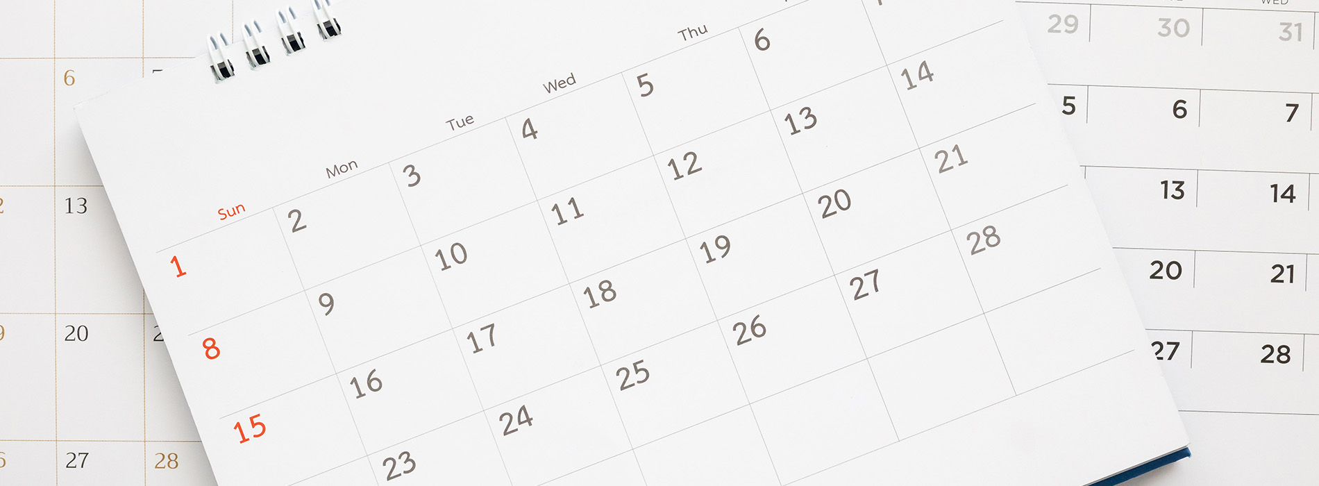 The image shows a printed calendar with dates, displayed on a surface next to a digital calendar on a screen.