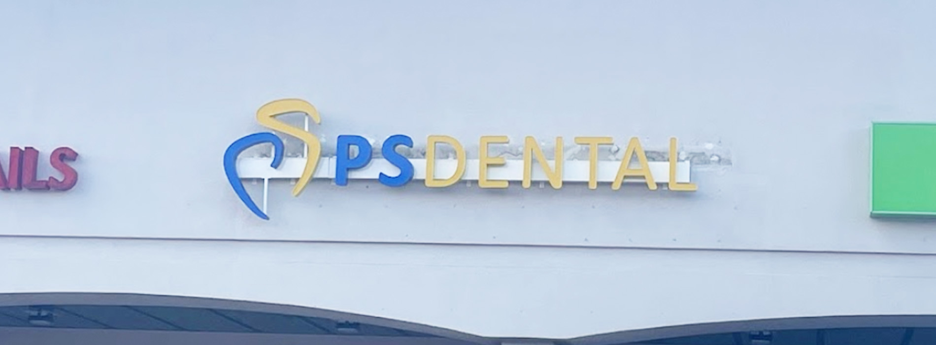 The image shows a storefront with a sign indicating  PS Dental  along with another sign for a dental clinic, set against a clear sky background.