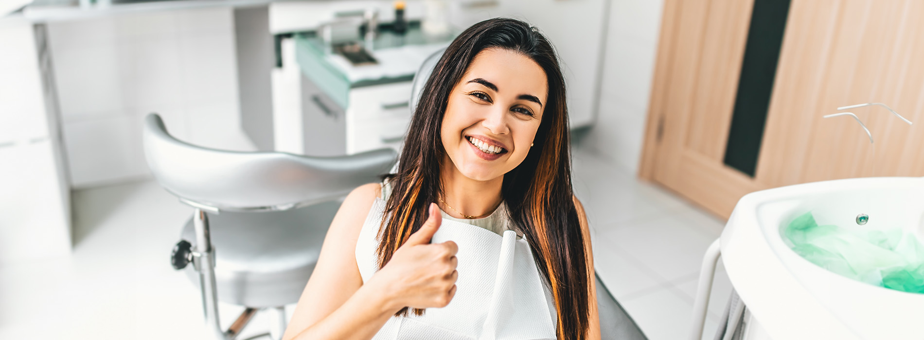 Woman giving thumbs up in front of sink, with green cleaning products in background.