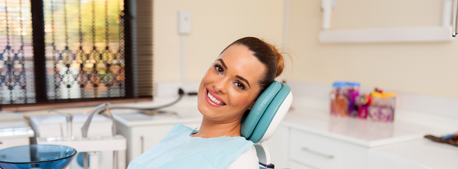 A woman sitting in a dental chair with a smile on her face.