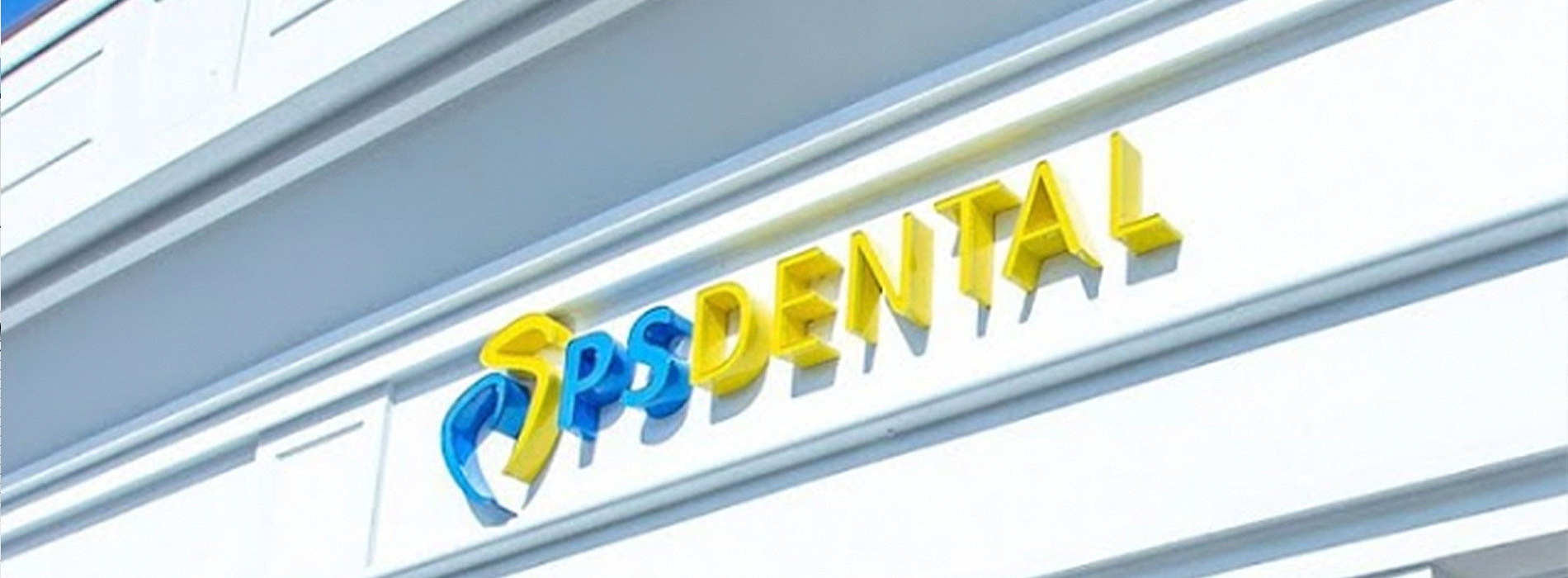 The image shows a sign with the word  SPONDAL  on it, indicating the name of a dental practice, set against a building facade.