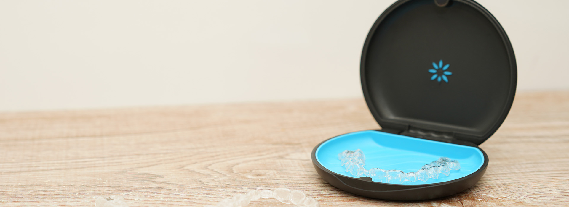 A black smart home device with a blue light on top, placed on a wooden surface.