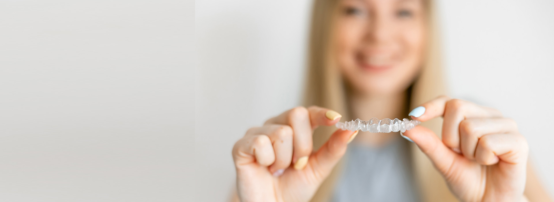 A person holding a small object, possibly jewelry, against a white background.