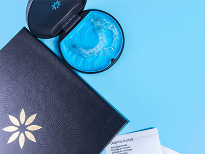 An open blue dental impression tray next to a closed package with a black and white label, featuring a logo and text, on a light blue background.