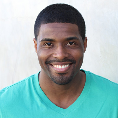 A man and woman are smiling and embracing each other outdoors during daylight.