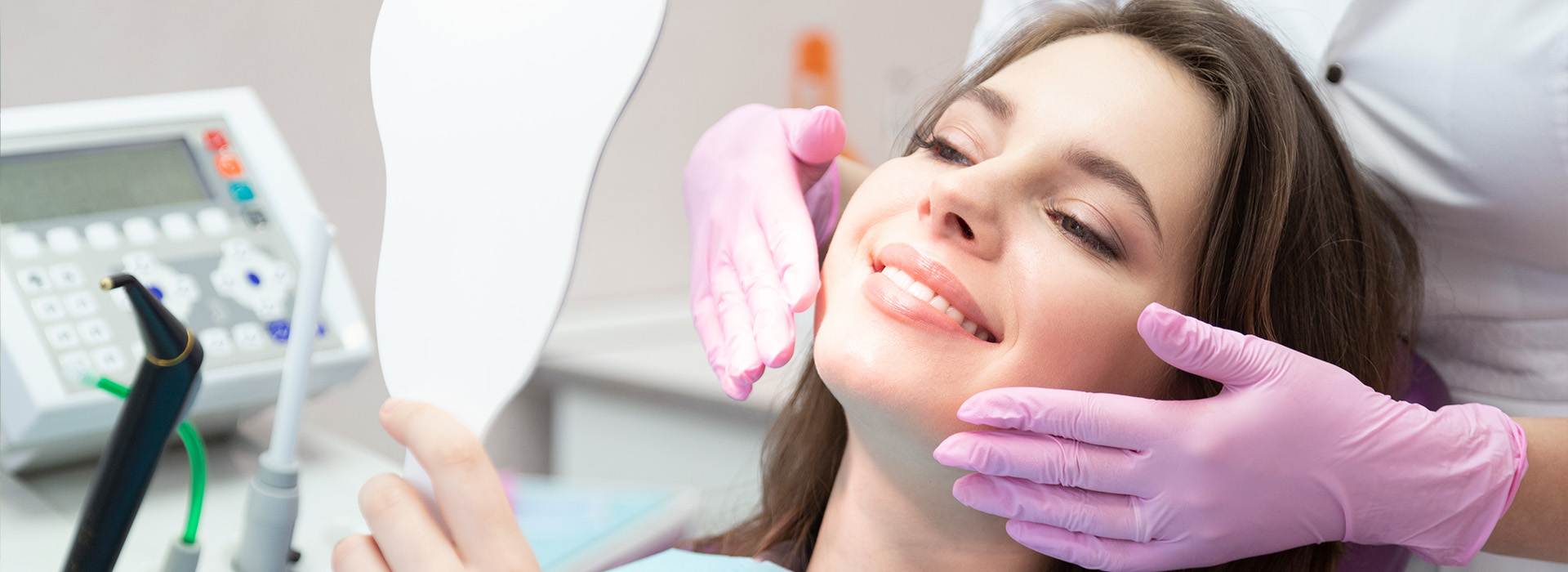 A woman receiving dental care with a dental hygienist using an ultrasonic cleaning device.