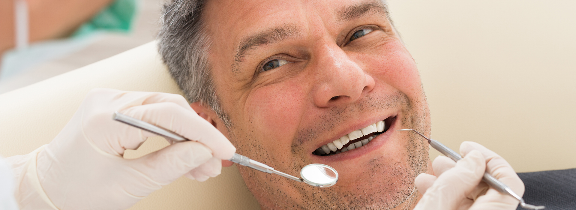 A man sitting in a dentist s chair with a smile on his face, receiving dental care.