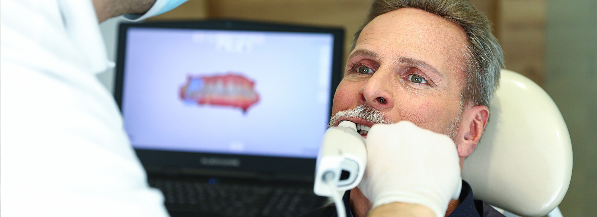 The image shows a person receiving dental care from a professional in a clinical setting.