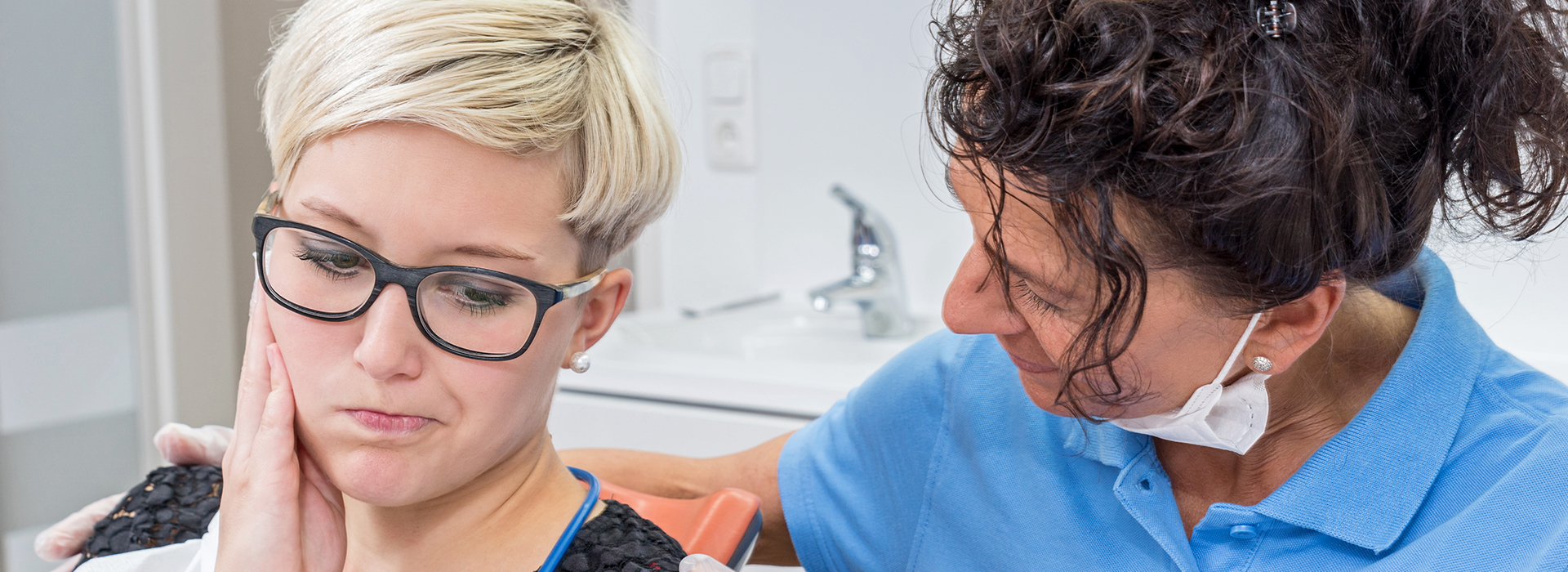 The image shows two individuals in a dental setting, where one person appears to be receiving dental care while another person, possibly a dental professional, attends to them.