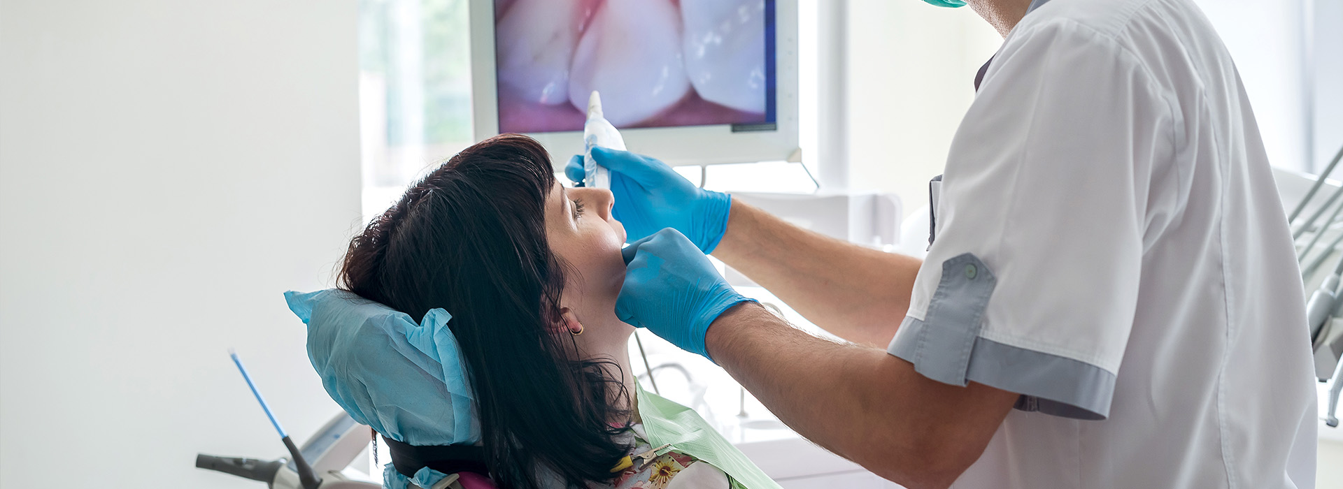 A dental professional performing a procedure on a seated patient.