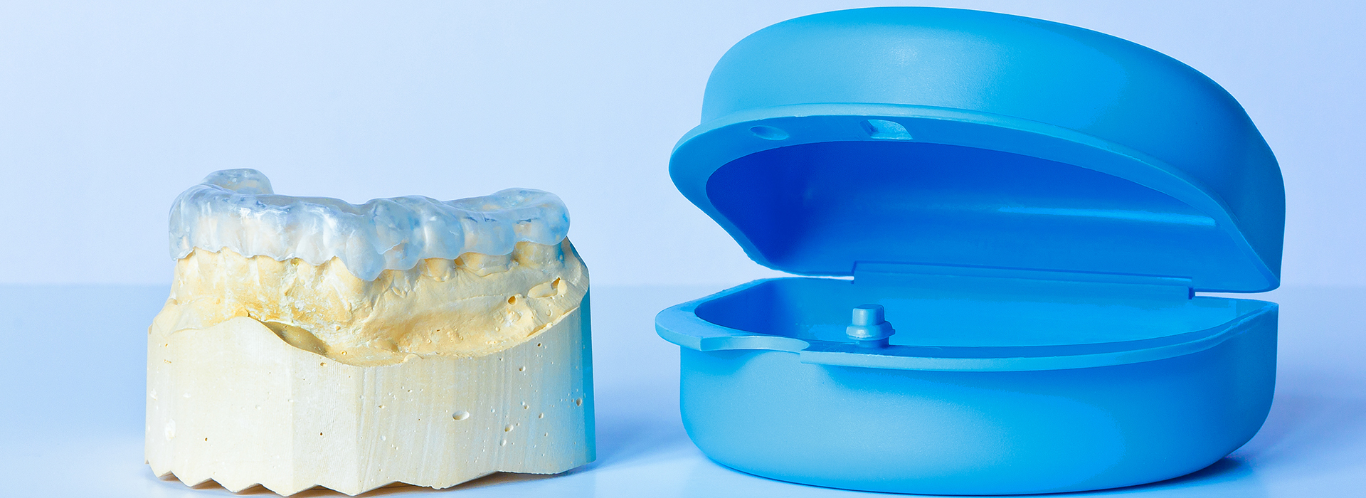 The image shows a blue dental implant on the right side and a yellow dental crown on the left side, both against a white background.