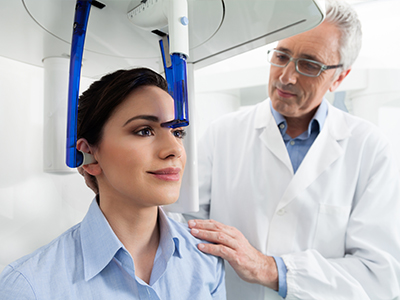 A medical professional using a device on a patient s head during a dental examination.