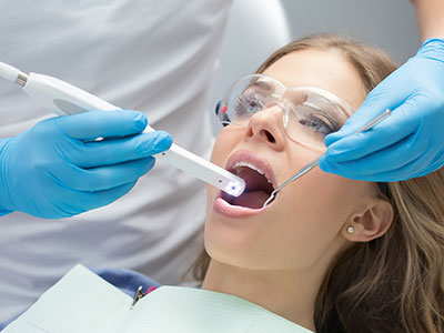 This image shows a dental professional using an electric toothbrush on a patient s teeth during a dental cleaning appointment.