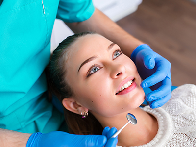 A dental hygienist performing a cleaning procedure on a patient s teeth with the aid of a dental mirror.