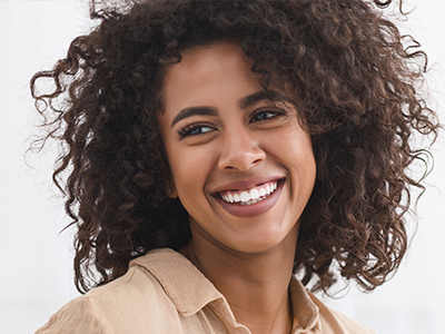 The image shows a person with curly hair smiling at the camera.